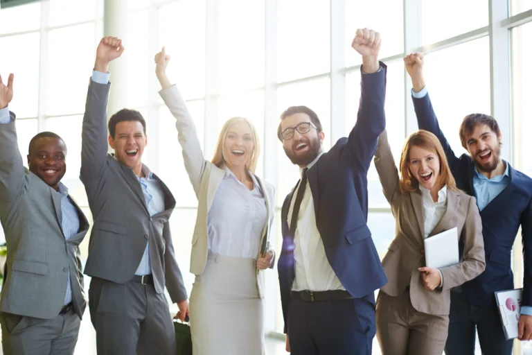 Grupo de profissionais sorridentes comemorando uma conquista no ambiente corporativo